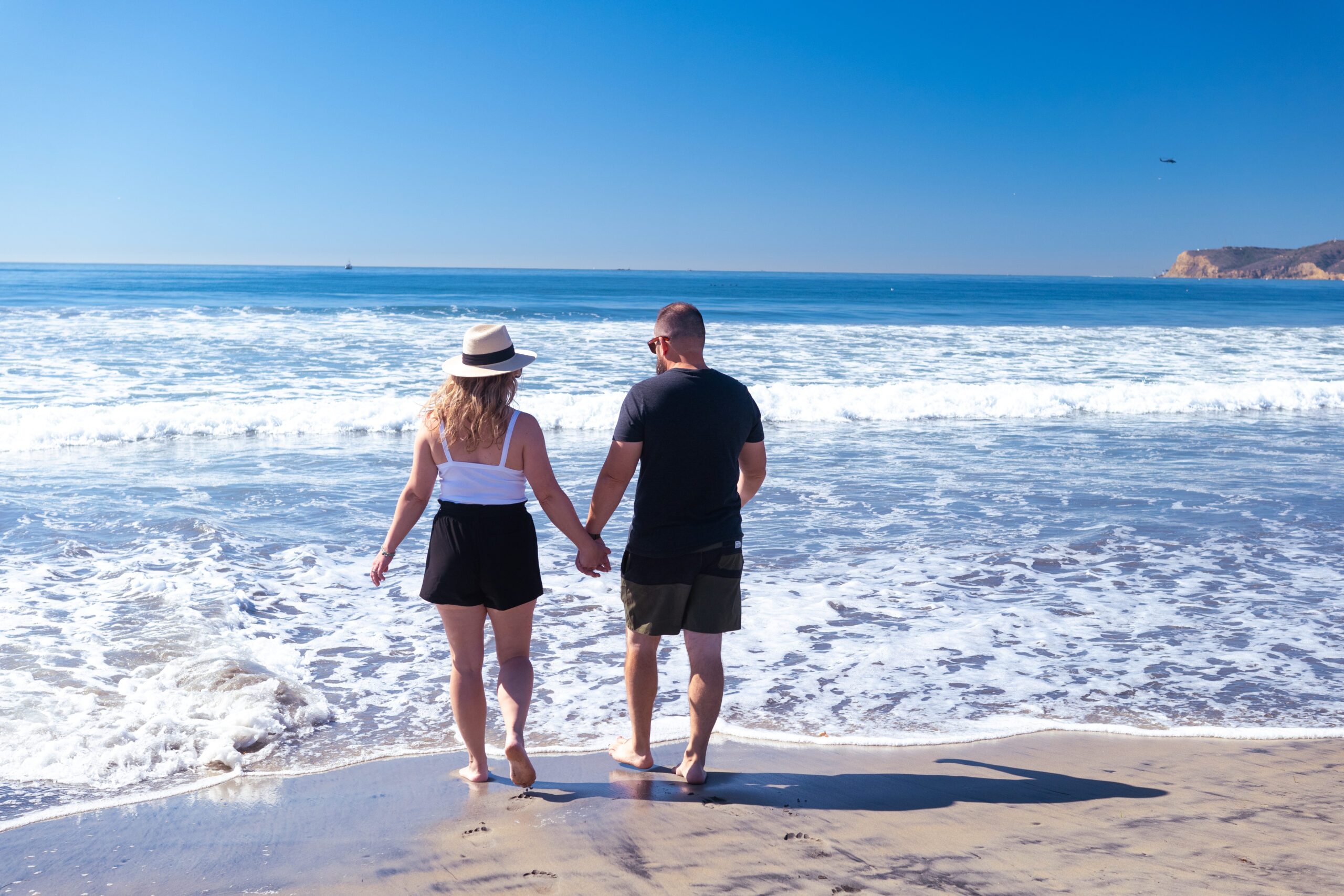 couple holding hands on the beach in coronado