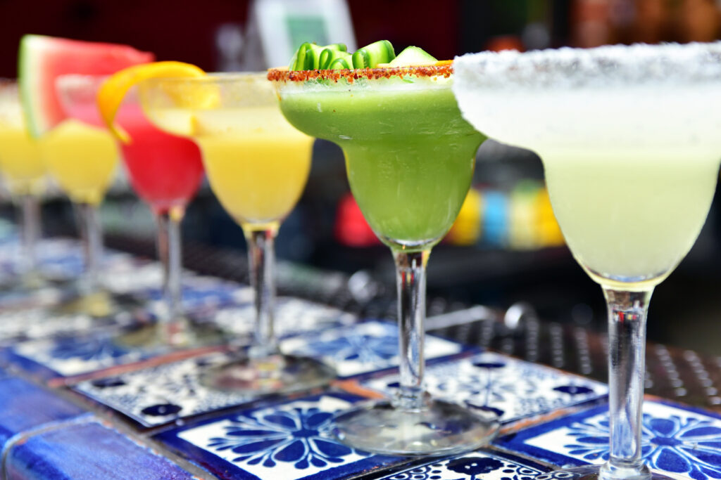 Colorful margaritas lined up on tile bar