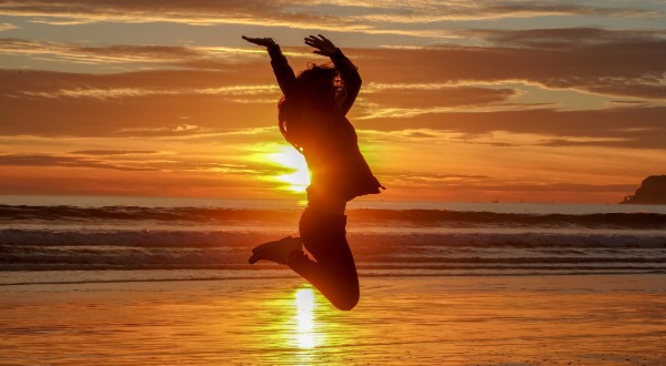 women jumping on the beach at sunset