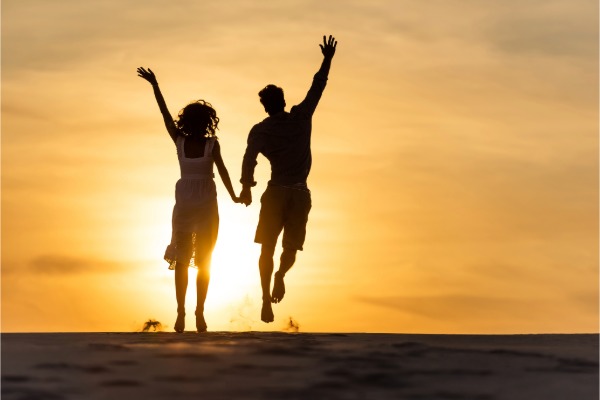 couple jumping on the beach at sunset